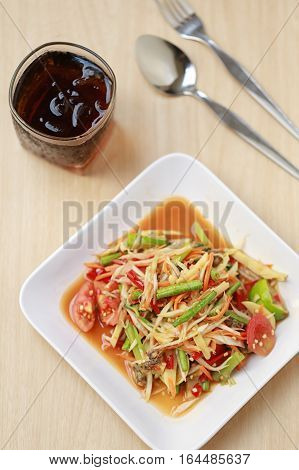 SOM TUMThai foods or papaya salad in spicy taste and is popular in thailand on wooden table background.