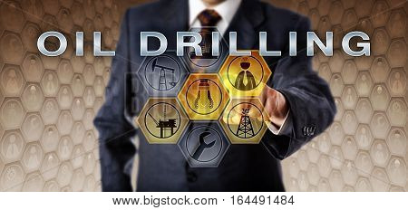 Male industrial manager in blue business suit touching OIL DRILLING on a virtual interactive control screen. Petroleum industry metaphor. Drill bit symbol and engineer icon are highlighted in yellow.