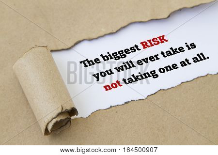 The biggest risk you will ever take is not taking one at all message written under torn paper.