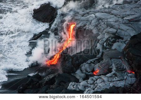 Lava comes out of lava tubes and meets ocean water on Big Island, Hawaii