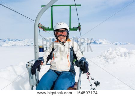 Happy female skier riding a lift. Skiing in sunny weather.