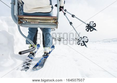 Back view of skier riding a lift. Skking in the mountains.