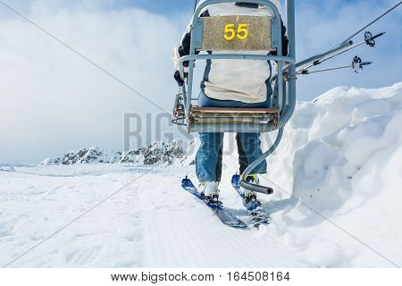 Back view of skier riding a lift. Skiing in the mountains.
