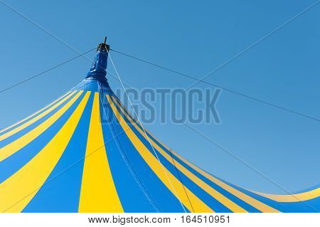 large yellow and blue circus big top canvas against a clear blue sky