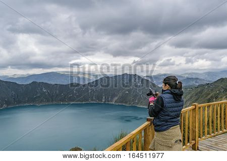 LATACUNGA, ECUADOR, FEBRAURY- 2016 - Young woman taking photo at viewpoint in Quilotoa lake Latacunga Ecuador