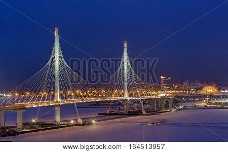 St. Petersburg Russia - January 3 2017: Express roads crosses the river icebound guyed bridge at night lighting in the winter.