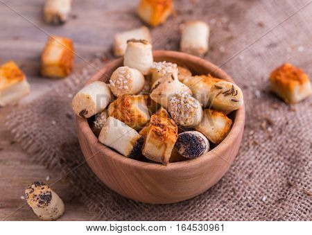 Salty party snacks in wooden bowl on natural background.