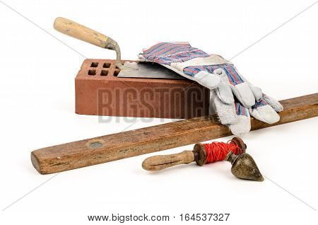 Old construction accessories trowel bricks plummet and level on white background.
