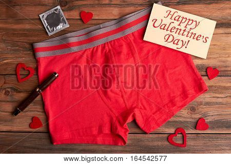 Boxer briefs and condom. Valentine's Day card, pen, hearts. Hot celebration of winter holiday.