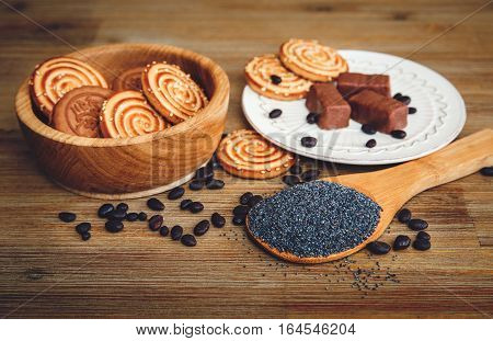 There are Cookies,Candy,Chocolate Peas,Poppy;China Saucer,Tasty Sweet Food on the Wooden Background