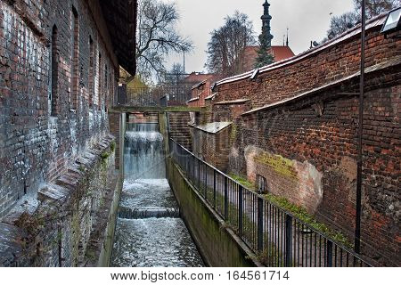 Restless waters Radunia Channel in the place of the former ancient water wheels. Inner of the medieval Great Mill in the Gdansk Poland. The Mill was built by the Teutonic Knights in 1350.