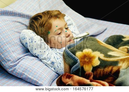 Sick child boy lying in bed with chicken pox