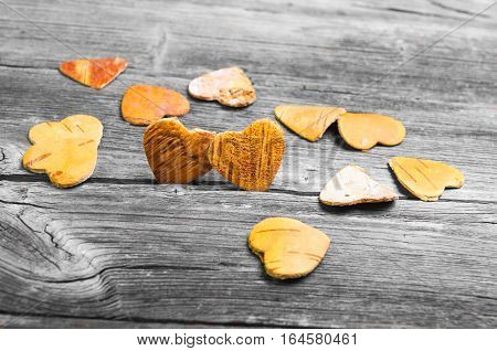Greeting Card Valentine's Day. Two hearts from the bark of a tree on a gray wooden background. Many wooden hearts valentines nearby.