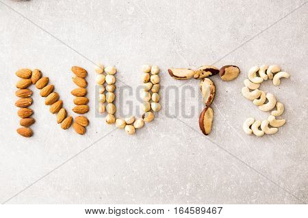 Word Nuts Spelled With Various Nuts On Stona Background. Assorted Mixed Nuts