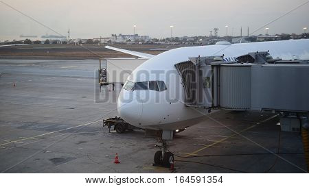 The plane is near the terminal in the international airport at dusk, wide angle