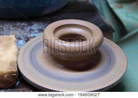 A clay pot on a pottery wheel, pottery craft, moulding the pot with your hands, sculpting hands