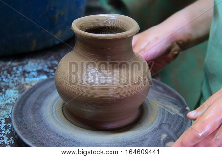 A clay pot on a pottery wheel, pottery craft, moulding the pot with your hands, sculpting hands