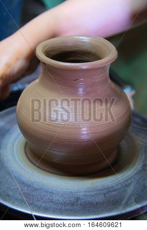 A clay pot on a pottery wheel, pottery craft, moulding the pot with your hands, sculpting hands