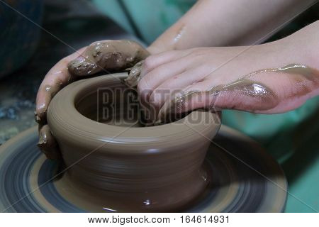 hands of a potter, creating an earthen jar on a pottery wheel