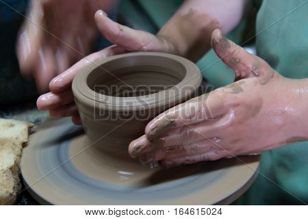 hands of a potter, creating an earthen jar on a pottery wheel