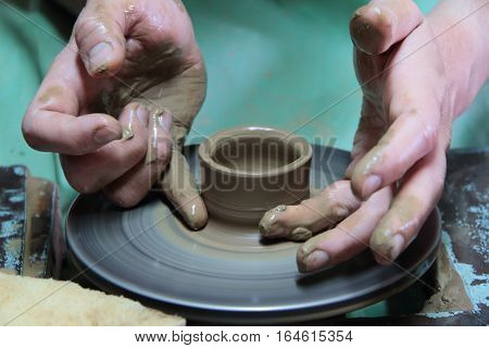 hands of a potter, creating an earthen jar on a pottery wheel