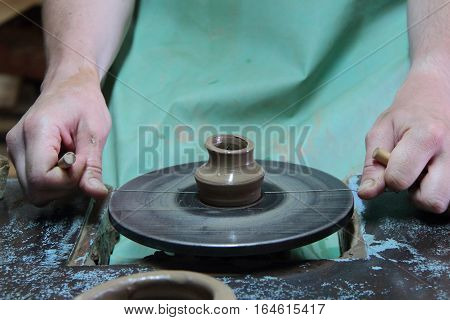 hands of a potter, creating an earthen jar on a pottery wheel