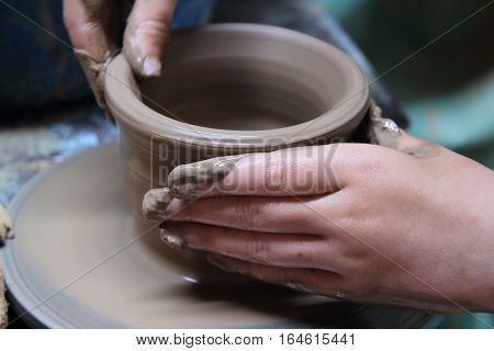 hands of a potter, creating an earthen jar on a pottery wheel