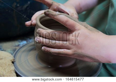hands of a potter, creating an earthen jar on a pottery wheel