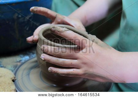 hands of a potter, creating an earthen jar on a pottery wheel