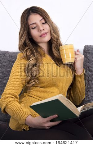 Girl in a yellow dress reading and drinking coffee