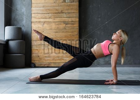 Young slim blond woman in yoga class making asana exercises. Girl do purvottanasana, upward plank pose. Healthy lifestyle in fitness club. Stretching