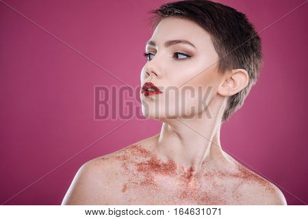 Confident look. Pleasant professioanl young model looking aside and posing against pink background