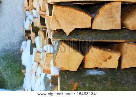 Stacked firewood in winter under the snow. Stock photo
