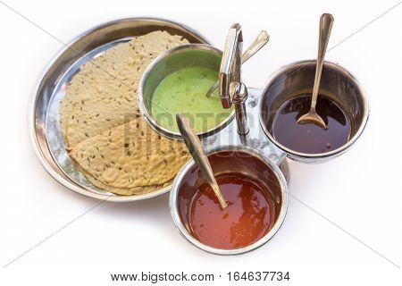 Indian bread served with the traditional assortment of sauces, in the typical tableware, on a white background