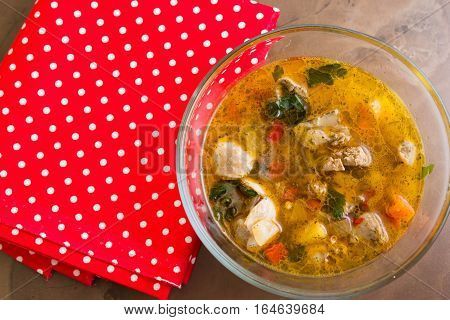 Vegetable soup with chicken giblets in a glass bowl on a marble table