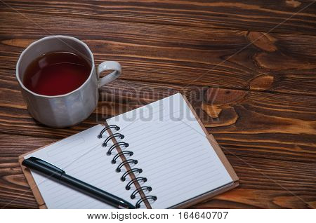 notebook on a table with a mug and a cup of tea