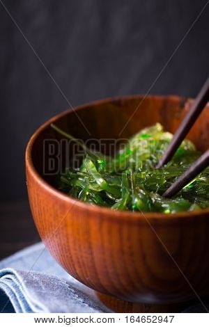 Chuka salad in the wooden bowl on the dark background