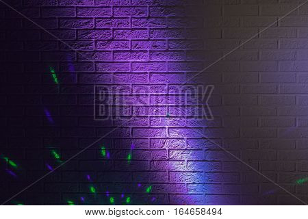 Textured brick wall lit by many colored lights