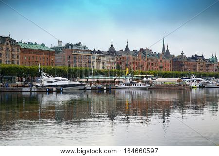 STOCKHOLM SWEDEN - AUGUST 20 2016: Many people walk and visit on Strandvagen street on Ostermalm distric with touristic sightseeing boats in Stockholm Sweden on August 20 2016.