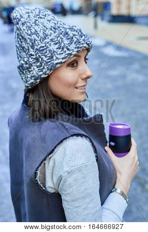 The girl with thermo cup, is walking through the old town