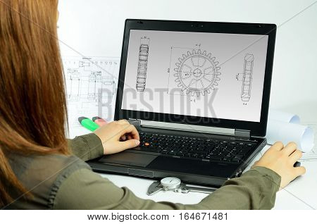 Young woman using CAD system in front of a laptop back view