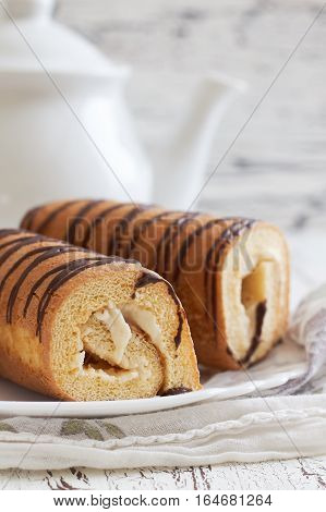 Sweet swiss rolls (roulade) with white cream served on white plate. Copy space