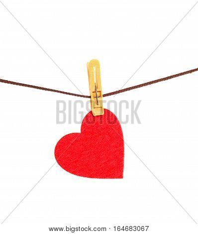 Red heart from dense fabric on a clothespeg on a rope. It is isolated on a white background