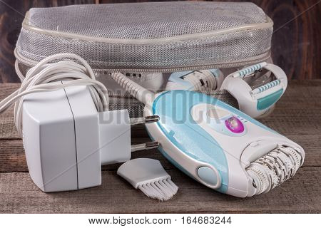 electric epilator with a bag on an old wooden background. Hair removal device