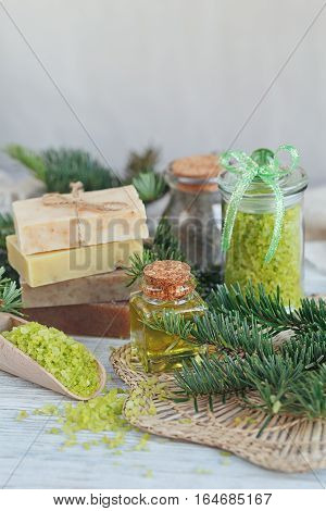 Natural sea salt and handmade soap with branch of pine on white wooden background. SPA concept.