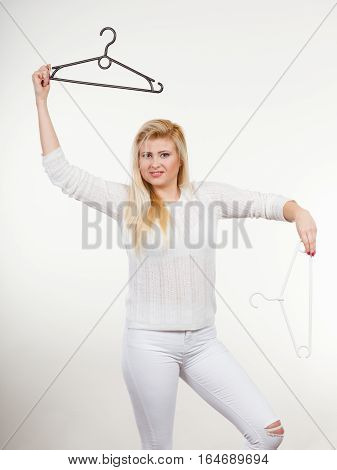 Wardrobe accessories concept. Blonde happy woman holding black clothes hanger having fun.