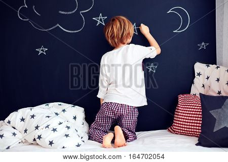 Cute Kid In Pajamas Painting Chalkboard Wall In His Bedroom