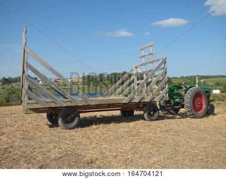 A old style hayrack hooked to a tractor ready to be loaded
 with feed for animals.