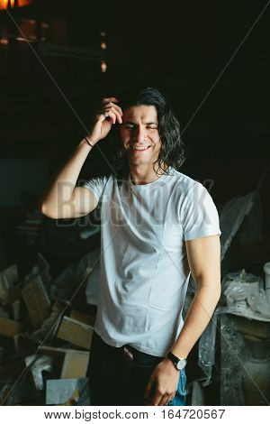Beautiful long-haired brunette smiling man in a white T-shirt