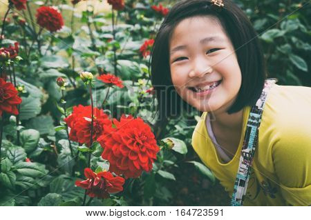 girl enjoy beautiful red dahlia in garden